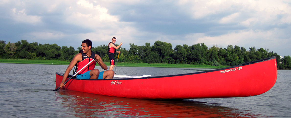 Single person in canoe with single person on paddleboard behind